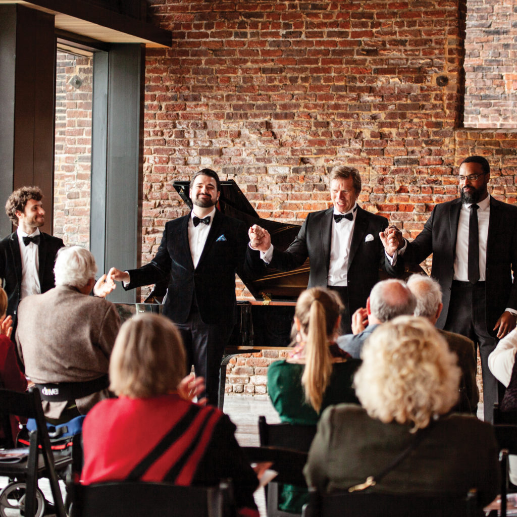 For men in suits bow after their opera performance "Crossing" in the ACWM Tredegar lobby